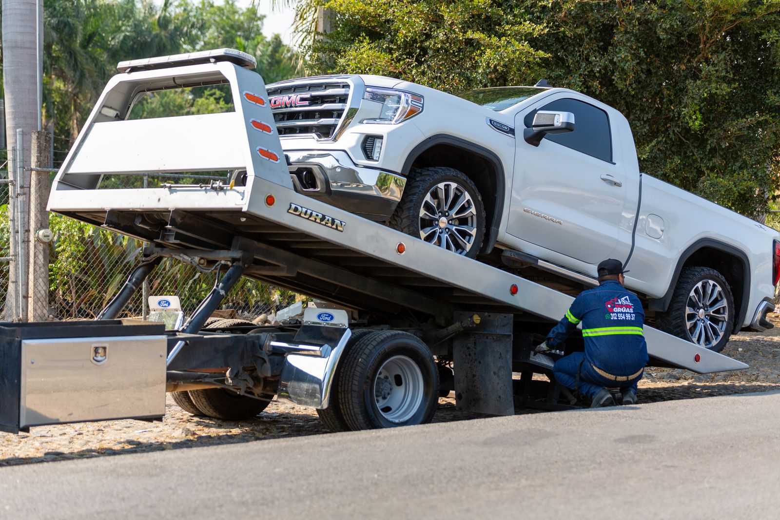 A pickup truck being winched onto a flatbed carrier
